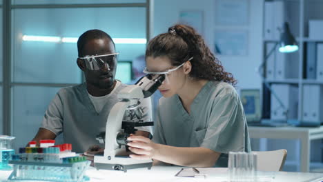 multiethnic scientists working with microscope in lab