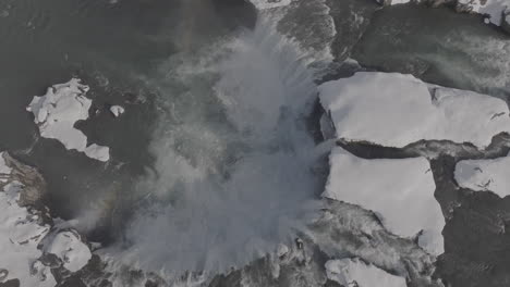 birds eye aerial view of godafoss waterfall, iceland, cold glacial water and snow capped canyon