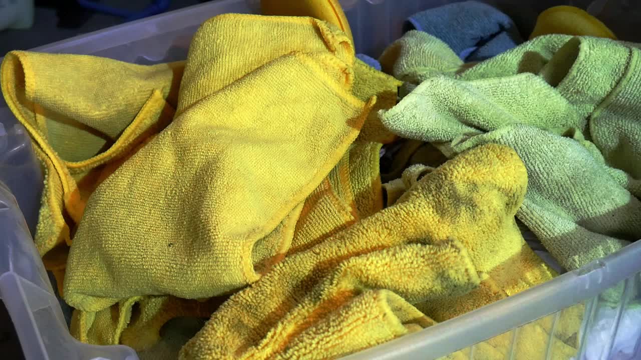 Close up throwing dirty micrfiber towels into laundry basket