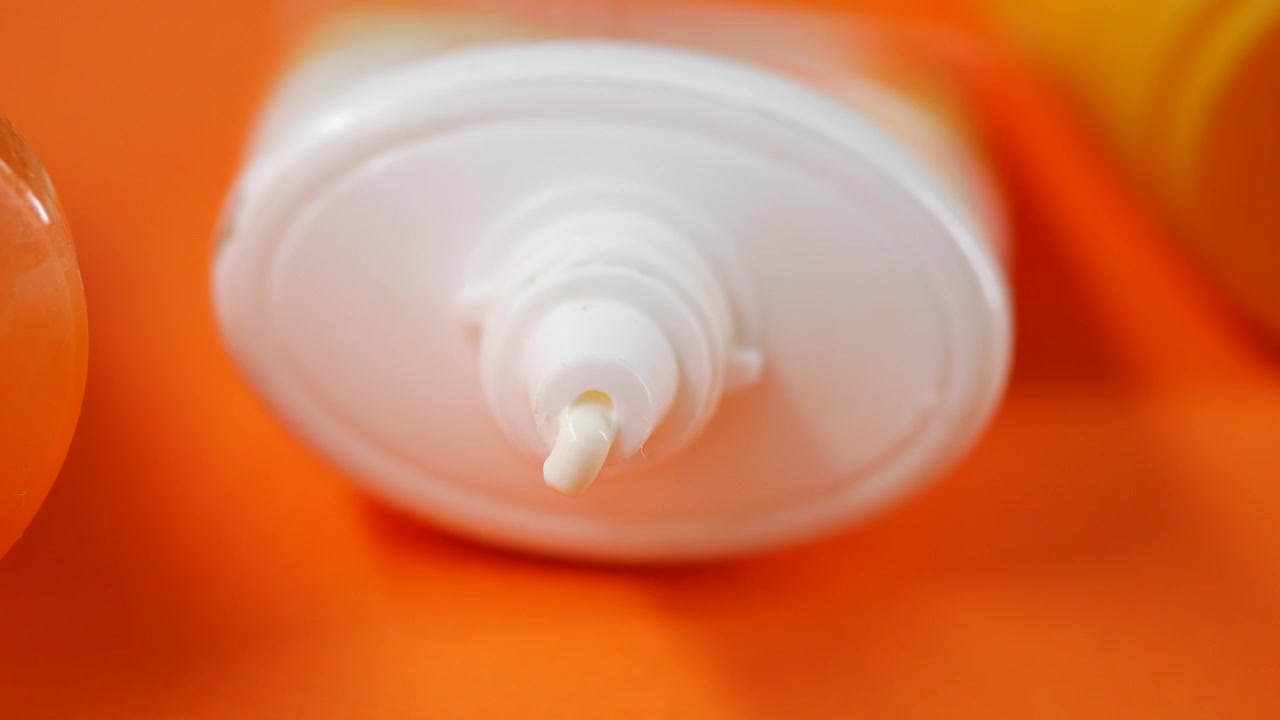 White Cream Dispensing from a Tube on Orange Background