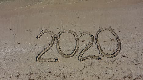 twenty twenty written in the sand and grows in size as camera gets closer