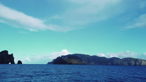 Rippling-Water-Through-The-Famous-Rock-Formation-In-New-Zealand---Hole-In-the-Rock---Tourist-Attraction---Low-Aerial-Shot