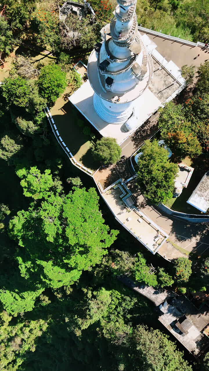 Amazing view of Ambuluwawa Tower Temple with multiple tourists on. Top perspective on the landmark in Gampola Town, Sri Lanka. Vertical video.