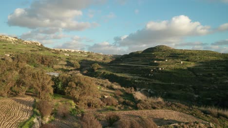 aerial: flying above farmland in malta with sun setting during golden hour