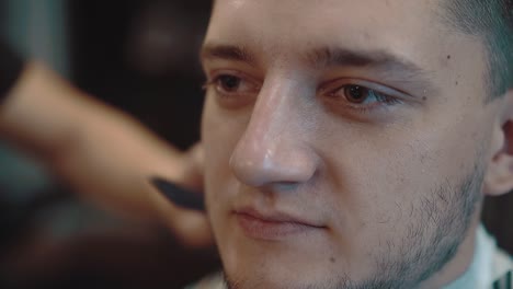 young man sits in a barber shop he is made up with a beard close-up slow motion