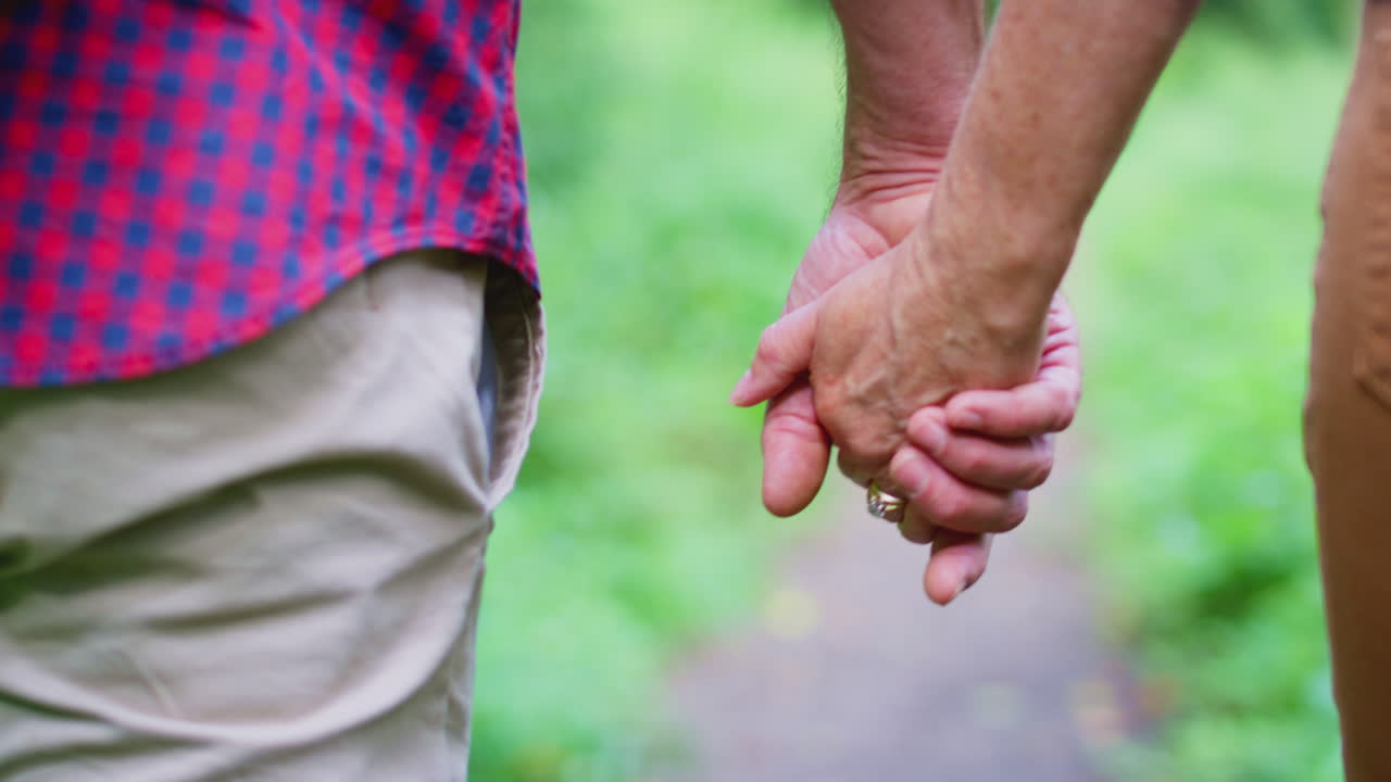 사랑 하는 성숙 한 부부 가 손 을 잡고 함께 시골 의 길 을 따라 산책 하는 장면