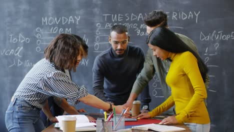 grupo multiétnico de jóvenes que planean proyectos parados en el escritorio y hablando entre ellos