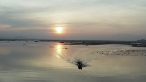 en la majestuosa puesta de sol sobre el embalse con el barco de pescadores volviendo a casa y bandadas de pájaros volando