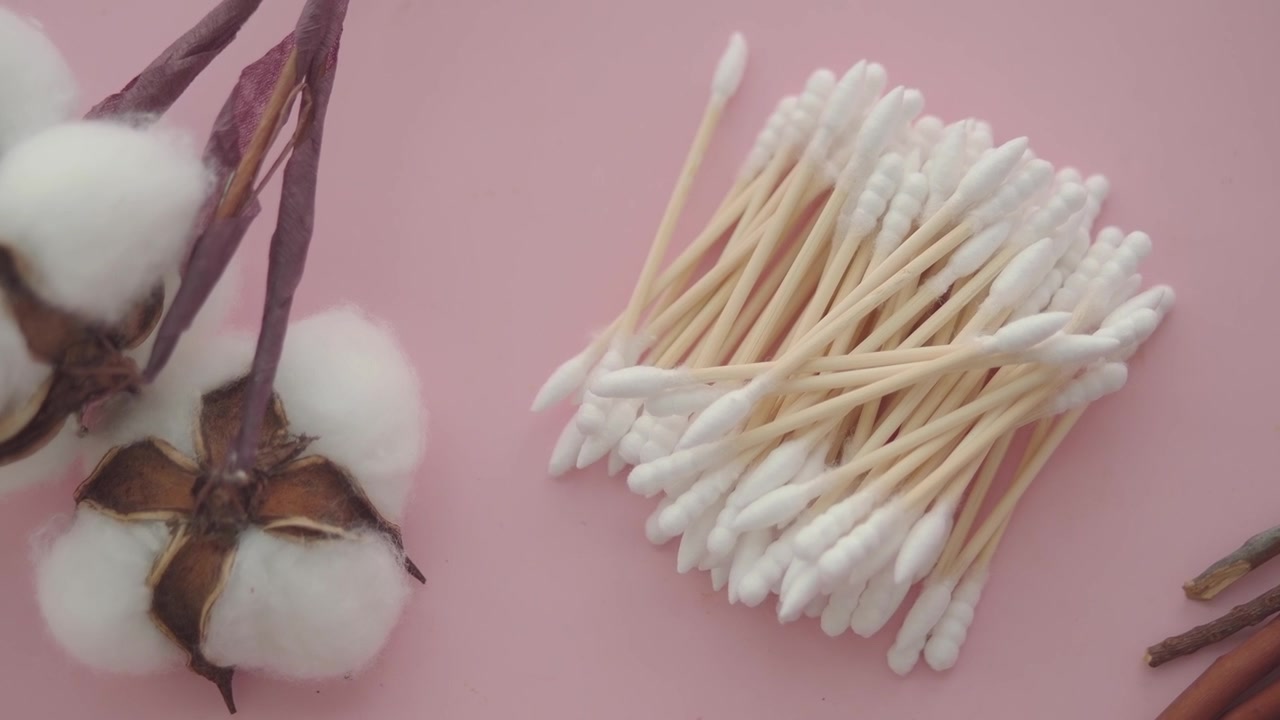 Cotton fioc e fiori di cotone su sfondo rosa