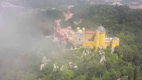 aerial drone flying through the clouds orbiting around the palacio da pena in portugal