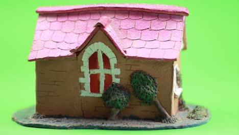 Kleines-Keramikhaus-Mit-Rotem-Dach-Auf-Grünem-Hintergrund