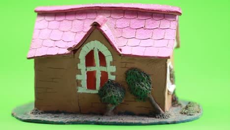 small ceramic house with red roof on green background