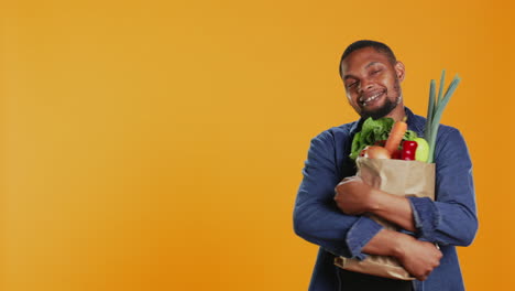 modelo masculino abrazando su bolsa de papel llena de comida orgánica de cultivo doméstico