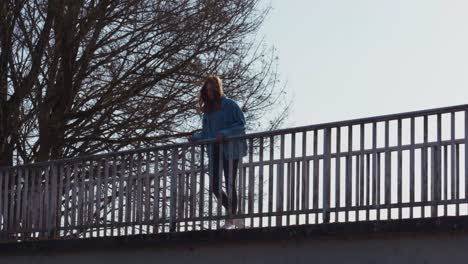 girl standing on a bridge thinking