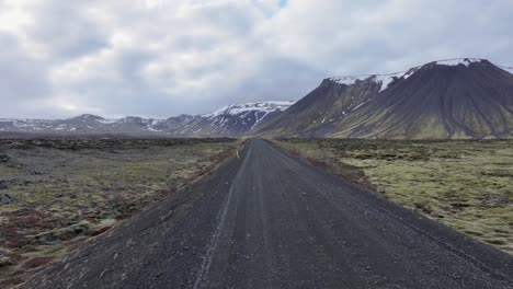 un vehículo en las tierras altas de islandia, paisajes de musgo, colinas, llanuras abiertas con un cielo azul profundo, nubes espumosas, océano brillante en la distancia