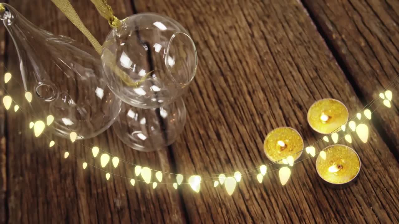 Animation of string lights, candles and christmas decorations on wood floor