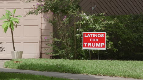 Un-Césped-En-Dallas,-Texas,-Con-Un-Cartel-De-Latinos-Por-Triunfo-Clavado-En-El-Césped-Frente-A-Una-Casa