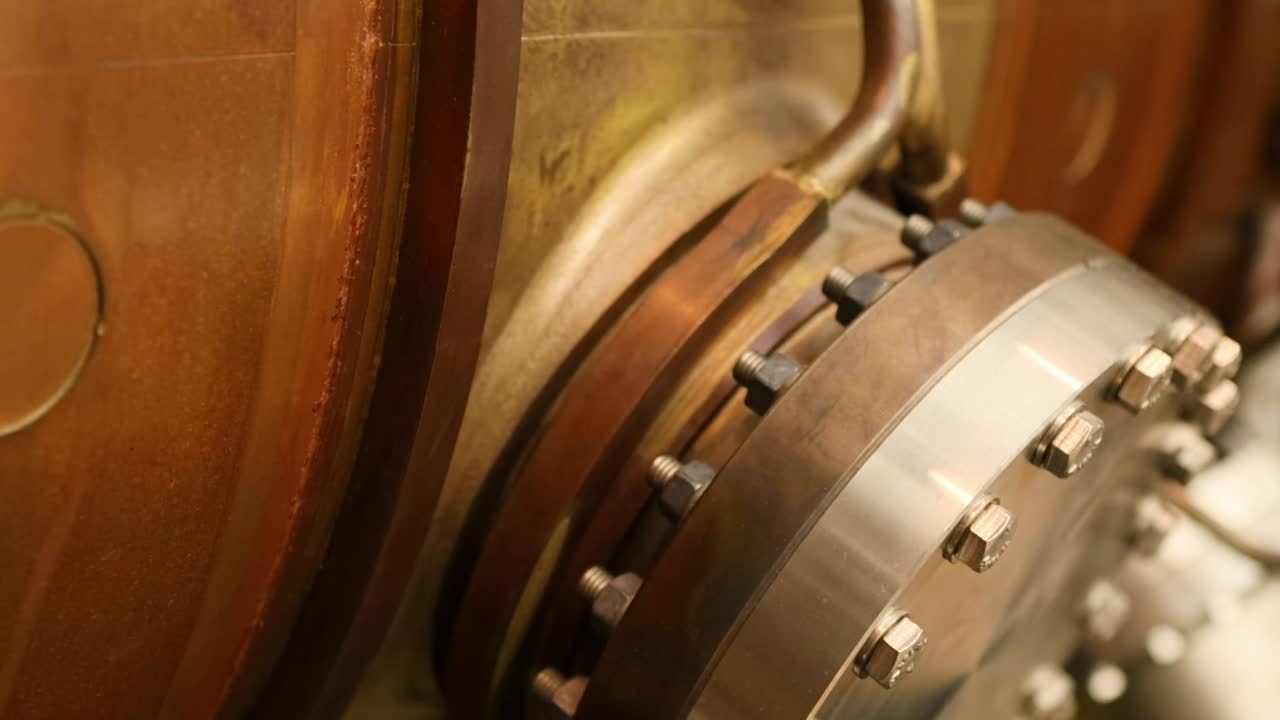 Detailed view of a bolted flange with metallic components and pipes in an industrial setting.
