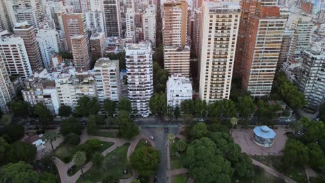 dolly in flying over barrancas de belgrano park revealing neighborhood buildings at sunset, buenos aires, argentina