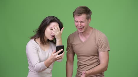 젊은 부부가 함께 전화를 하고 나쁜 소식을 듣고 있습니다.