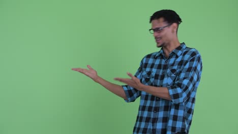 joven feliz y guapo hombre hipster africano mostrando algo