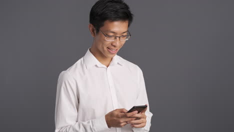 아시아인 남자가 스마트폰을 확인하고 미소 짓고 있습니다.