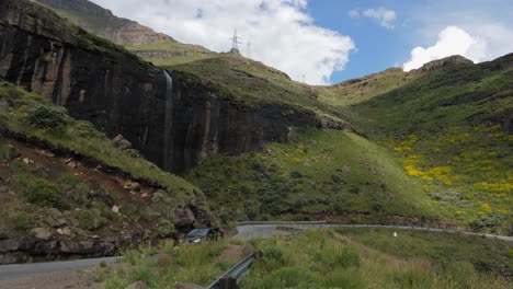 Car drives past dramatic vertical waterfall on Lesotho&#039;s Moteng Pass