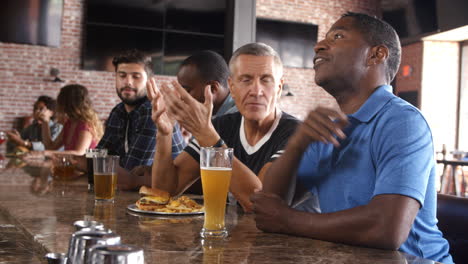 group of male friends watching game in sports bar