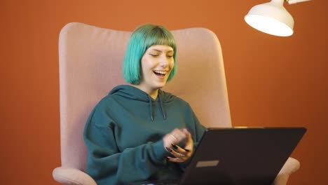 mujer joven mirando la computadora portátil aplaudiendo.