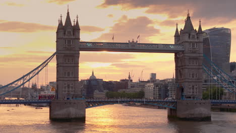 El-Autobús-De-Londres-Cruza-El-Emblemático-Puente-De-La-Torre-Contra-El-Ardiente-Cielo-Del-Atardecer,-Teleobjetivo-Aéreo