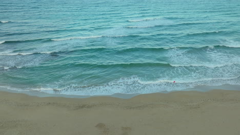 Calm-waves-crashing-over-golden-sand-in-Cyprus-at-dusk---aerial