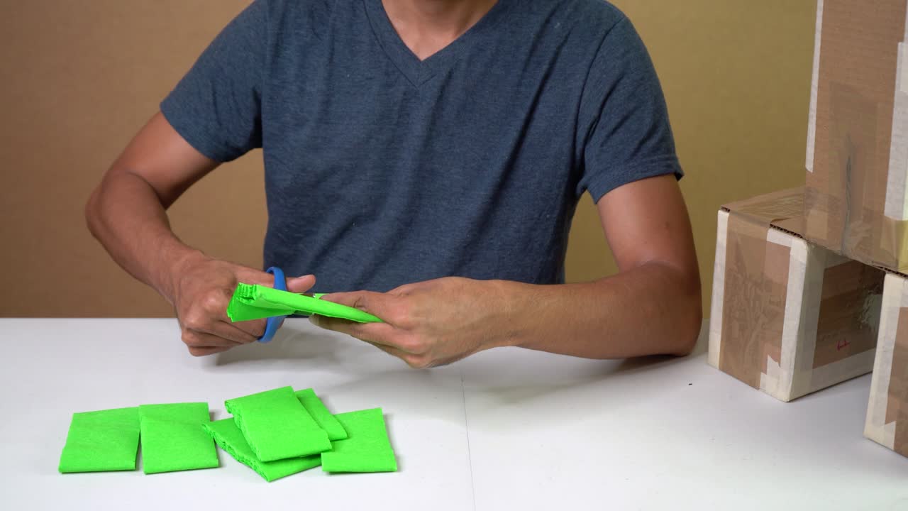 Workshop scene of craftsman cutting green crepe paper for handmade craft project