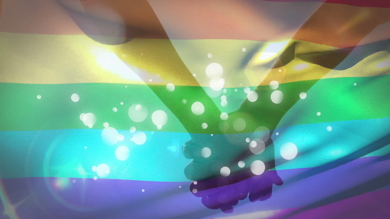 animación de una bandera arco iris ondeando sobre una pareja que se sostiene de la mano y manchas blancas parpadeantes