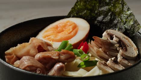 hand adding chili flakes to a bowl of delicious ramen