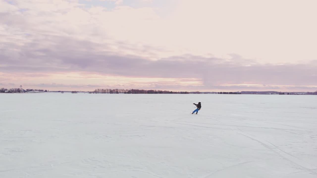 un uomo sta sciando sulla neve in un campo al tramonto. il suo paracadute tira. kite surf sulla neve..