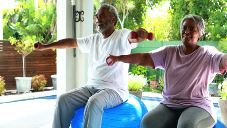 senior couple exercising with dumbbell at home