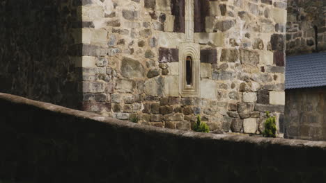 mtsvane monastery bell tower with cross on top behind low stone wall