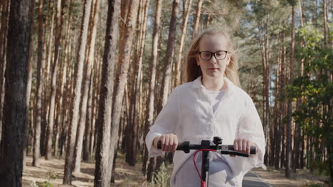 blonde child rides a scooter in the park