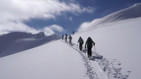 group of backcountry skiers ascending skintrack and nearing summit