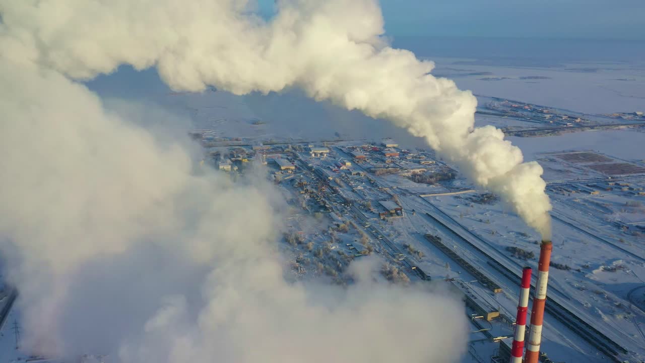Aerial View of Industrial Complex in a Snowy Landscape with Smoke Emissions