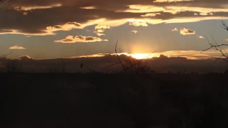 a charcoal grill smokes in the foreground as the sun sets