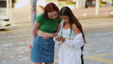 dos mujeres mirando un teléfono en la calle
