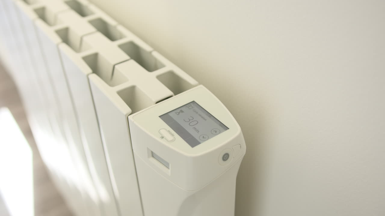 Female hand turning on and adjusting home heater. Close up, high angle