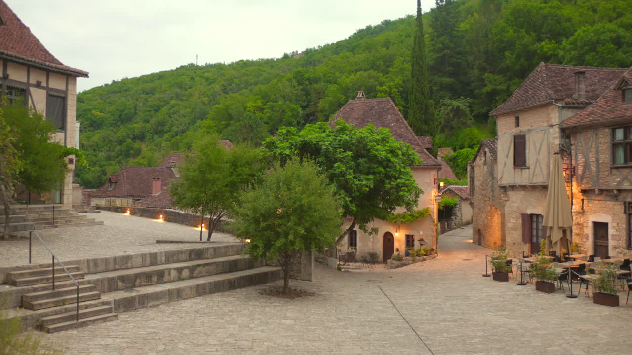 Smooth pan left across the medieval village of Saint-Cirq Lapopie, highlighting its stone houses and green hillside backdrop