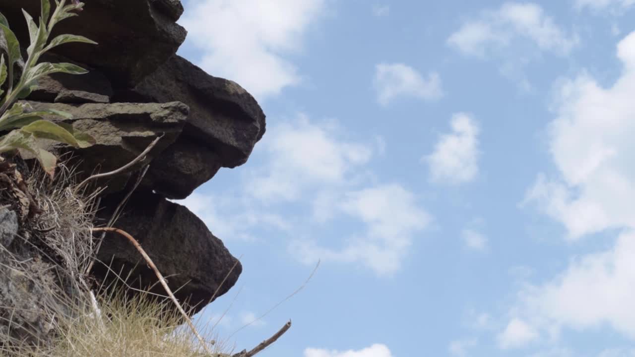 Craggy rocks on moors against blue cloudy sky tilting shot