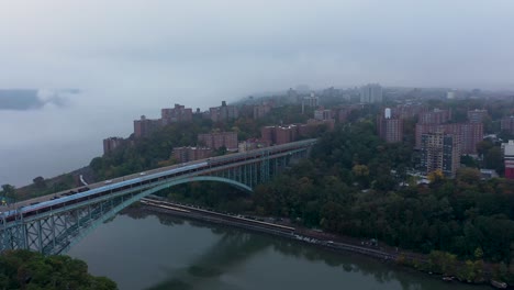 aerial back away from the henry hudson bridge with low fog over the river in the early morning