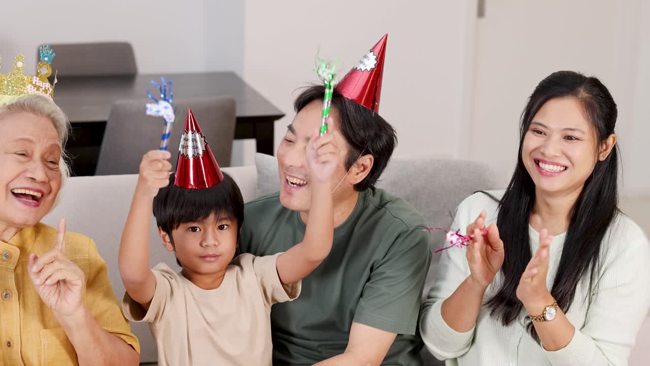 A family enjoys a birthday party at home, wearing hats and using party blowers, creating a joyful and festive atmosphere