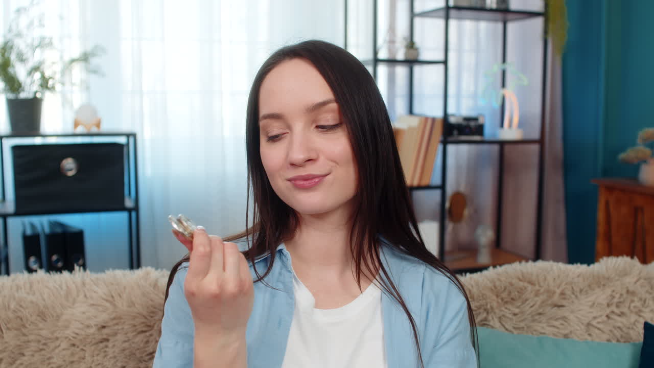 Young woman holding bitcoin coin excitedly surprised by cryptocurrency profit analyzing investment