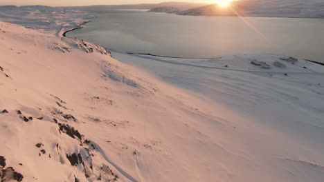 Schöner-Sonnenuntergang-Auf-Der-Bergseite-In-Richtung-Schneebedeckter-Farm-An-Der-Küste