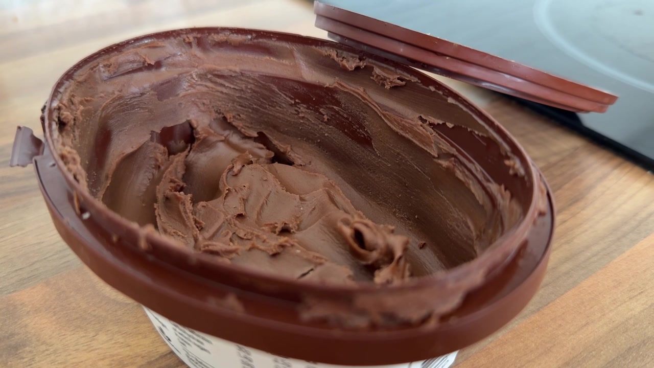 Vasetto aperto di crema spalmabile al cioccolato in primo piano, guarnizione cremosa al cacao per dessert e alimento processato zuccherato.